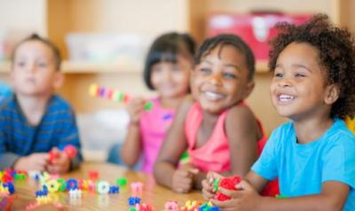 Four kis sitting with blocks in a learning environment.