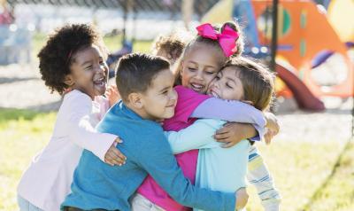 Young children on a playground hugging